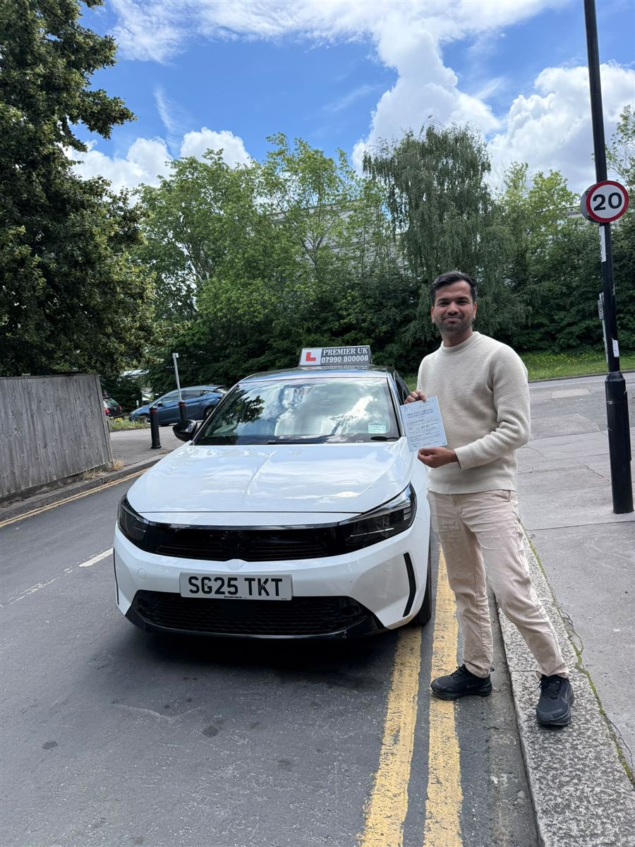 Vision Driving School learner holding his DVSA test pass certificate beside the tuition car