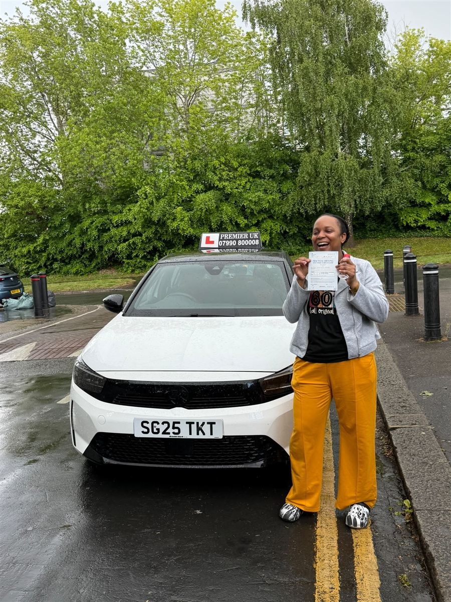 Delighted learner holding her driving test pass certificate beside the tuition car