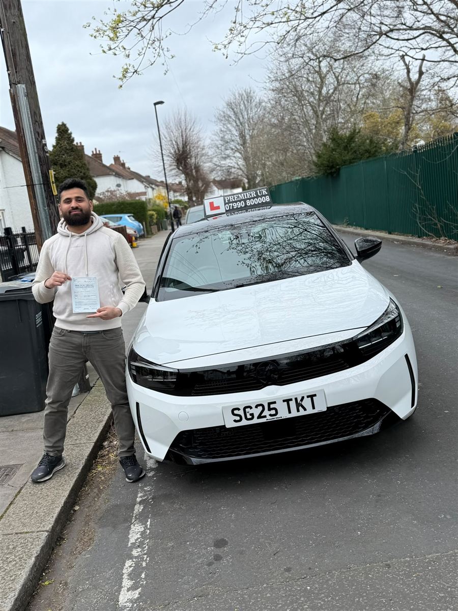 A happy learner standing beside the Vision Driving School tuition car after passing their driving test